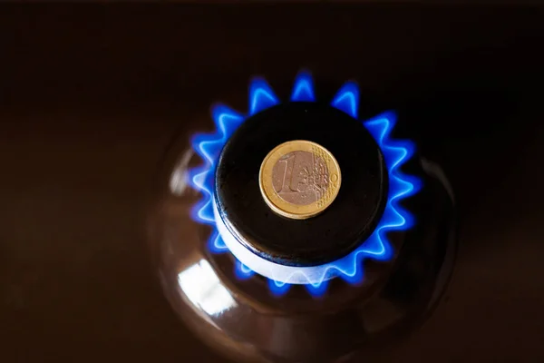 gas stove burner with one euro coin laid on top, burning natural gas with blue flame