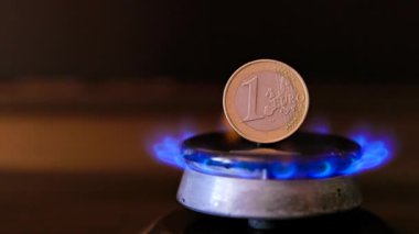 gas stove burner with one euro coin standing vertically on top, burning gas