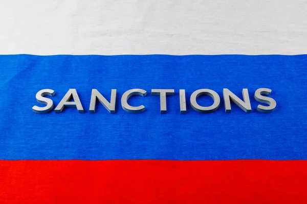 ロシアの三色旗に銀の金属文字で書かれた制裁という言葉は — ストック写真