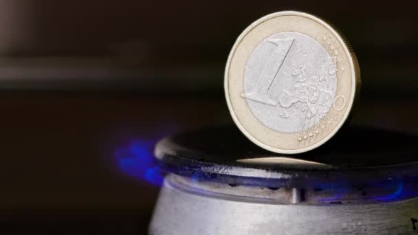 Gas stove burner with one euro coin standing vertically on top, burning gas — Stockvideo