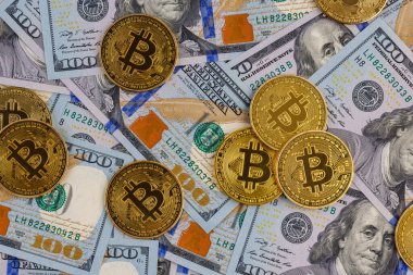 yellow bitcoin coins scattered over US dollar paper banknotes