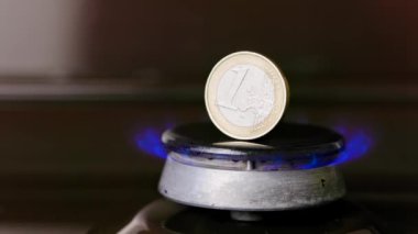 gas stove burner with one euro coin standing vertically on top, burning gas