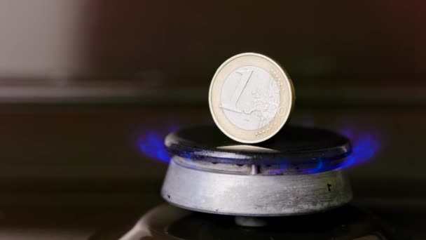 Gas stove burner with one euro coin standing vertically on top, burning gas — Vídeo de stock
