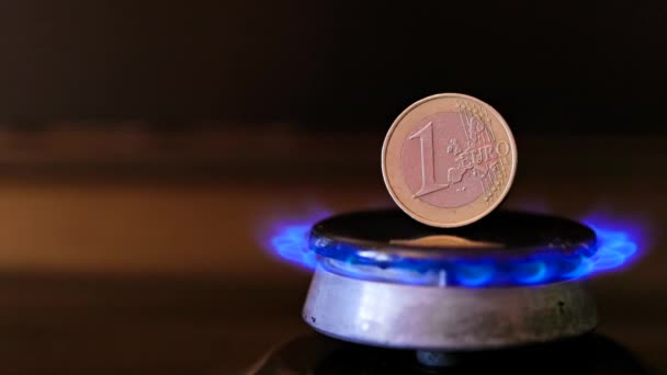 Gas stove burner with one euro coin standing vertically on top, burning gas — Stockvideo