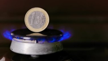 gas stove burner with one euro coin standing vertically on top, burning gas
