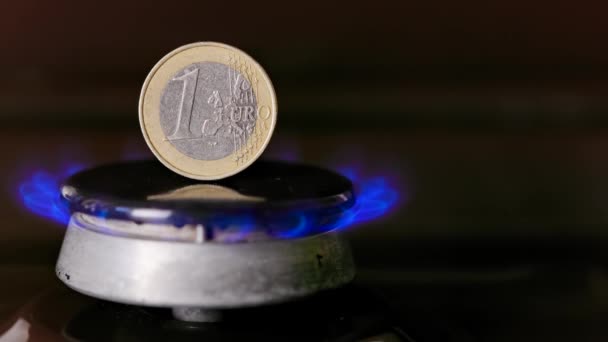 Gas stove burner with one euro coin standing vertically on top, burning gas — Vídeo de stock