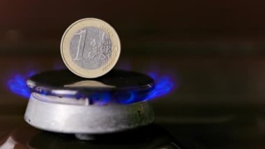 gas stove burner with one euro coin standing vertically on top, burning gas