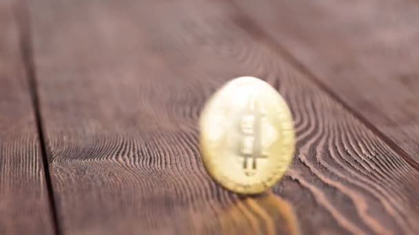 Bitcoin coin spinning on wooden background - close-up with slow-mo — Stockvideo