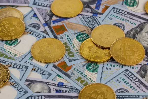 Yellow bitcoin coins scattered over US dollar paper banknotes — Stock Photo, Image