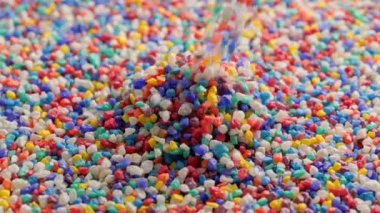 crushed colored stones puring on flat surface, forming a small pile in slo-mo