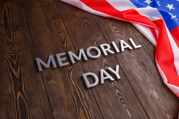 The words memorial day laid with silver metal letters on wooden board surface with crumpled usa flag — Zdjęcie stockowe