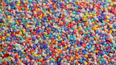 crushed colored stones on flat surface, slowly spinning, loopable closeup