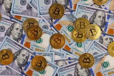 yellow bitcoin coins scattered over US dollar paper banknotes