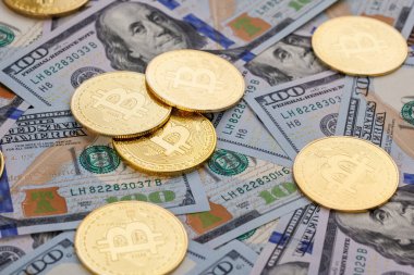 yellow bitcoin coins scattered over US dollar paper banknotes