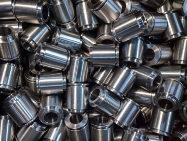 A lot of small equal shiny steel parts flat background. Raw metal surface after cnc turning light like silver