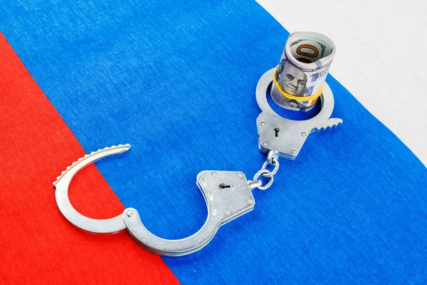 Roll of us dollar banknotes in a handcuffs on flat full-frame russian flag — Foto de Stock