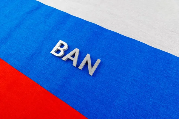 The word ban laid with silver metal letters over fabric Russian Federation flag — Stock Fotó