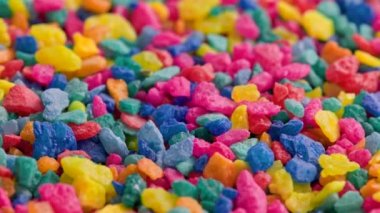 crushed colored stones on flat surface, slowly spinning, loopable closeup
