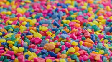crushed colored stones on flat surface, slowly spinning, loopable closeup