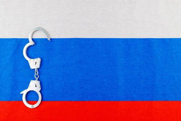 Silver metal opened handcuffs laid on Russian flag full-frame background — Foto Stock