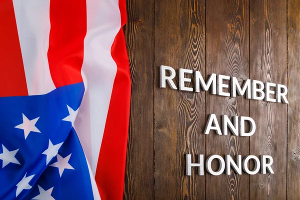 Words remember and honor laid with silver metal letters on wooden background with USA flag on the left side — Stockfoto