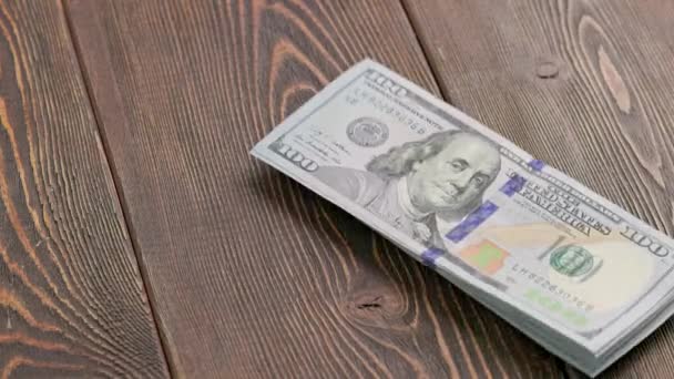 Stack of US dollar banknotes dropping on wooden surface and bouncing — Stockvideo