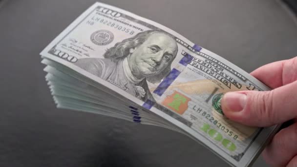 Χειραψία μικρή στοίβα των εκατό δολαρίων ΗΠΑ χαρτονομίσματα πάνω από γκρι φόντο — Αρχείο Βίντεο