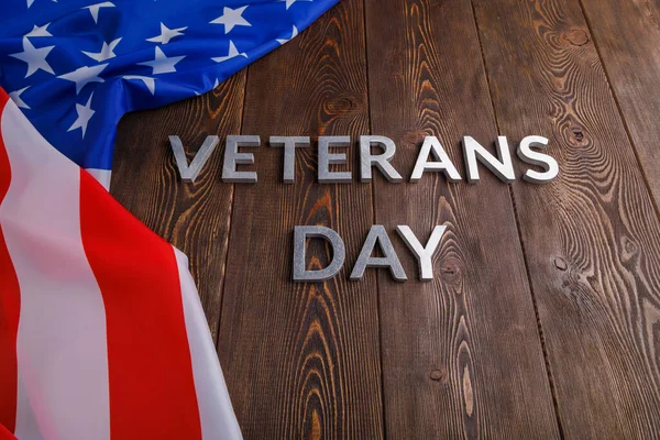 Orden veteraner dag läggs med silver metall bokstäver på träskiva yta med skrynklig usa flagga — Stockfoto