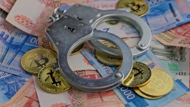Roataing background of russian ruble banknotes with bitcoin coins and handcuffs — Stockvideo
