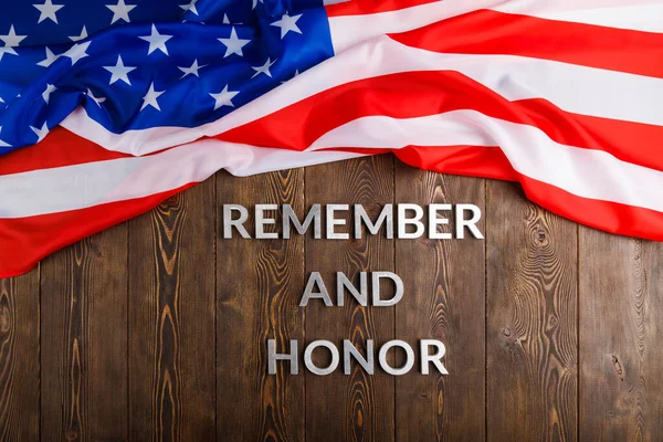 Words remember and honor laid with silver metal letters on wooden background with USA flag above — Stockfoto