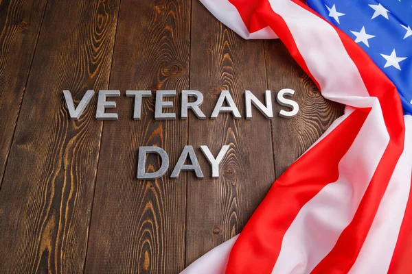 Orden veteraner dag läggs med silver metall bokstäver på träskiva yta med skrynklig usa flagga — Stockfoto