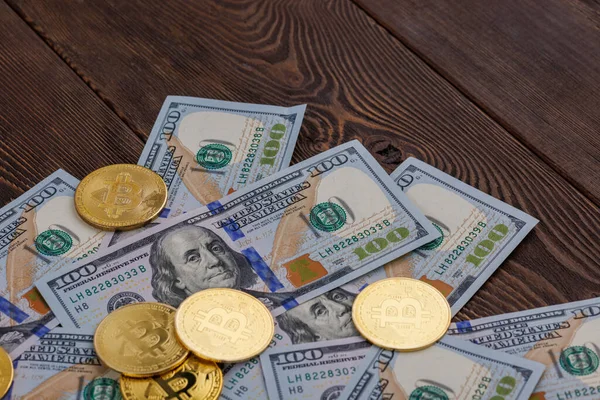 Bitcoin coins scattered over US dollar paper banknotes on wooden background — Stok fotoğraf