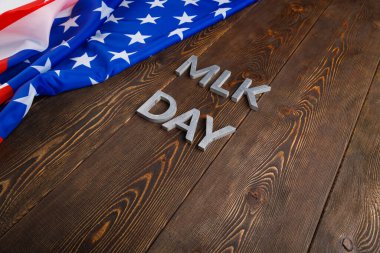 MLK günü, ahşap yüzeyinde gümüş metal harflerle ve sol tarafında buruşuk Amerikan bayrağıyla yazılıydı.