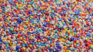 crushed colored stones on flat surface, slowly spinning, loopable closeup