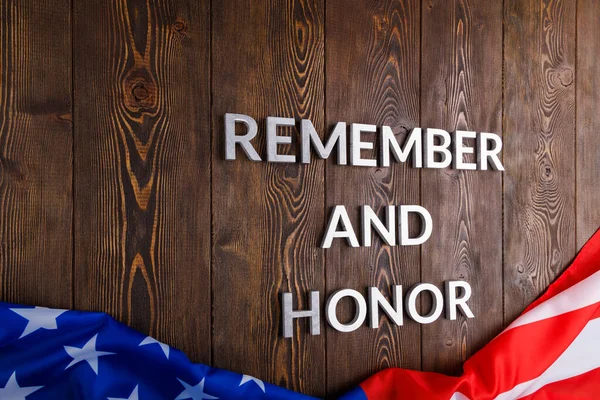 Words remember and honor laid with silver metal letters on wooden background with USA flag underneath — Stockfoto