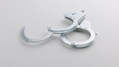 slowly spinning silver handcuffs on white background