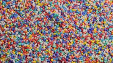 crushed colored stones on flat surface, slowly spinning, loopable closeup