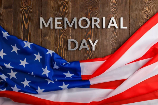 The words memorial day laid with silver metal letters on wooden board surface with crumpled usa flag — Zdjęcie stockowe