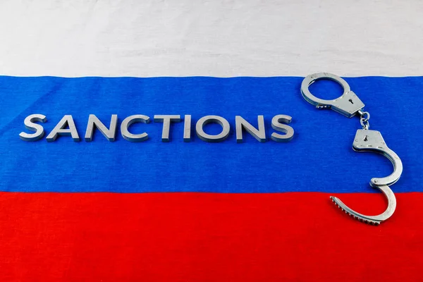 ロシアの三色旗に銀の金属の文字で書かれた制裁という言葉は — ストック写真