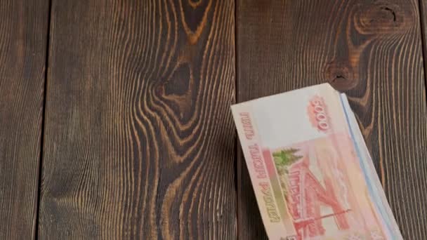 Стопка российских рублей банкноты падают на деревянную поверхность и скольжения — стоковое видео