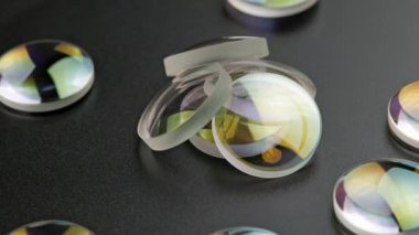 small pile of round glass converging lens pieces spinning on flat black surface