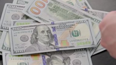 caucasian hand counting small stack of hundred us dollar banknotes