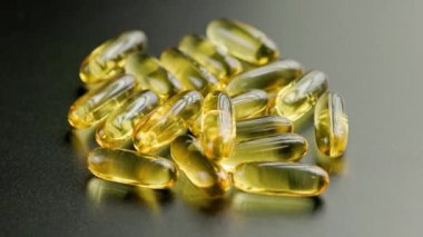 group of golden transparent pills with liquid medicine rotating on black surface