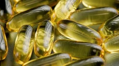 golden transparent pills with liquid medicine rotating, full-frame close-up