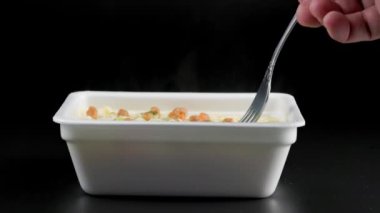 caucasian hand with fork taking cooked instant noodles from styrofoam container