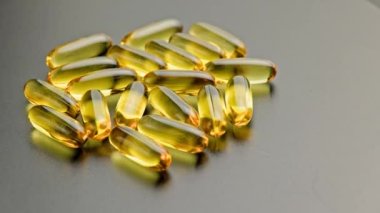 group of golden transparent pills with liquid medicine rotating on black surface