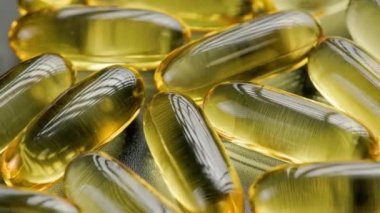 golden transparent pills with liquid medicine rotating, full-frame close-up