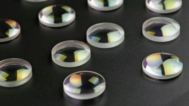Round glass converging lens pieces spinning on flat black surface — Vídeos de Stock