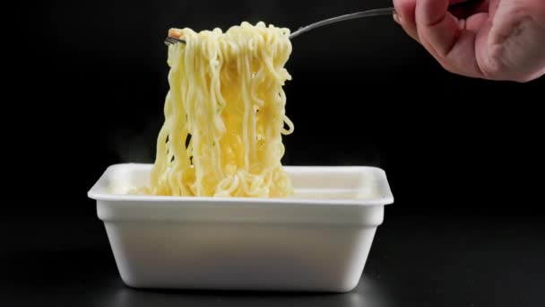Hand with fork stirring and cooling cooked instant noodles — Stock Video