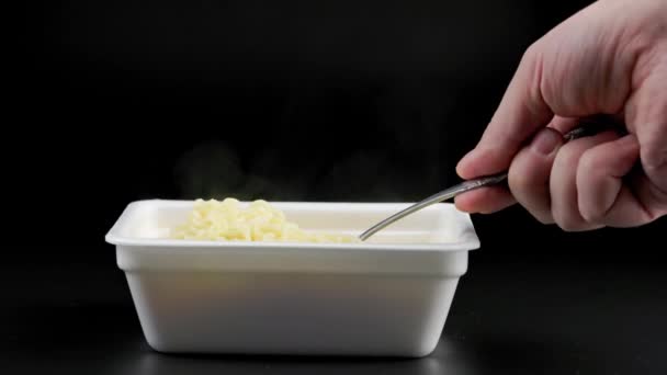 Hand with fork stirring cooked instant noodles from styrofoam container — Wideo stockowe